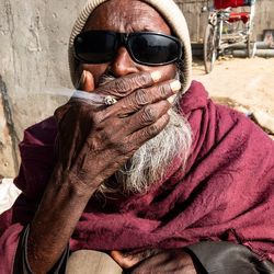 Portrait of senior man wearing sunglasses while smoking cigarette outdoors