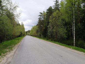 Empty road amidst trees against sky