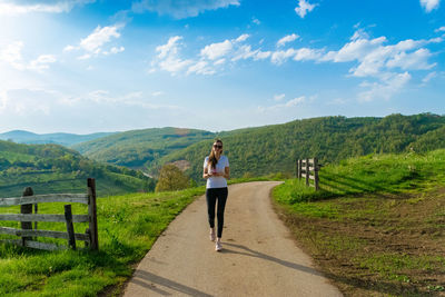 Full length of woman walking against mountains on road