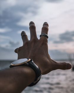 Cropped hand against sky during sunset