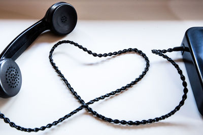 High angle view of telephone receiver making heart shape on table