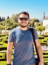 Portrait of young man wearing sunglasses standing against sky