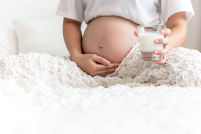 Midsection of baby girl relaxing on bed at home