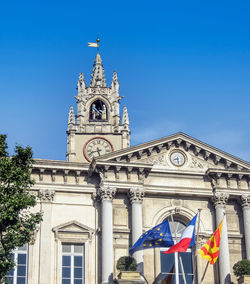 Low angle view of flags on building against blue sky