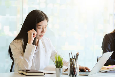 Young woman using mobile phone while sitting on table