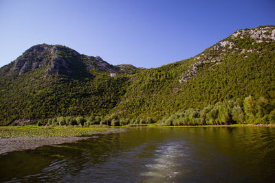 Scenic view of lake and mountains against clear sky