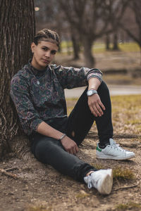 Portrait of girl sitting against tree trunk