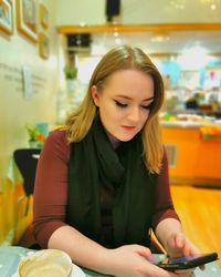 Young woman looking away while sitting on table