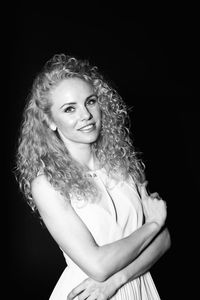 Portrait of a smiling young woman against black background