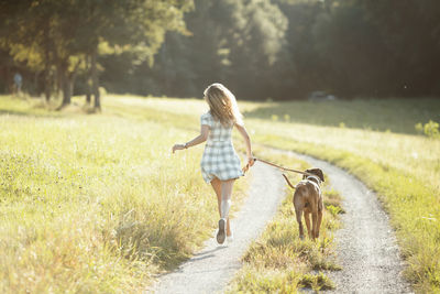 Rear view of woman with dog running on road