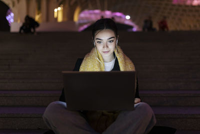 Teenager listening music and using laptop at night