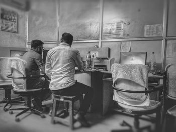 Rear view of people sitting on table