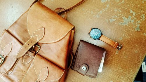 Close-up of backpack and wallet with wristwatch on table