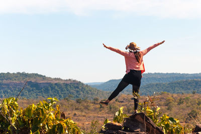 Full length of woman with arms outstretched against sky