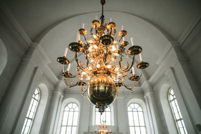 Low angle view of illuminated chandelier hanging in ceiling