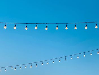 Low angle view of illuminated lights against clear blue sky