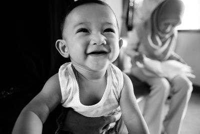 Close-up of person carrying smiling baby boy at home