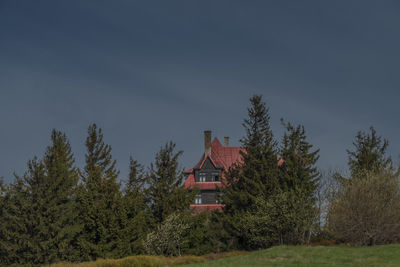 Trees and houses on field against sky