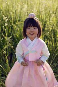 Korean national children pink costume on a four year old girl standing in a field with grass