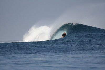 Man surfboarding in sea against sky