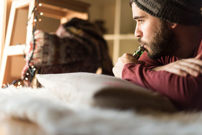 Young man looking away while sitting at home