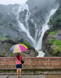 Full length of woman standing by waterfall