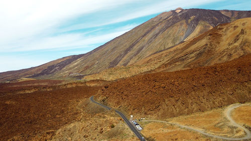 Scenic view of road by mountains against sky