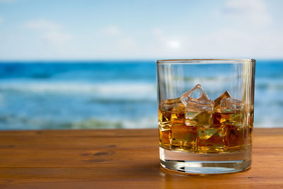 Close-up of beer on table against sea