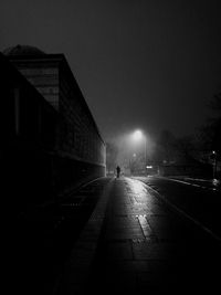 Road amidst illuminated city against clear sky at night
