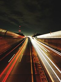 Light trails on railroad tracks against sky at night