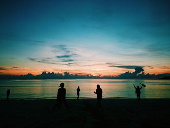 Silhouette people on beach against sky during sunset