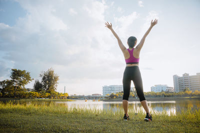 Full length of woman with arms raised against sky