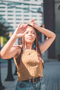 Young woman with arms raised standing in city