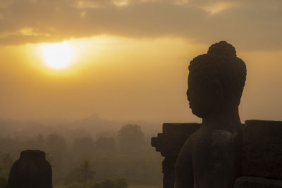 Silhouette statue against sky during sunset