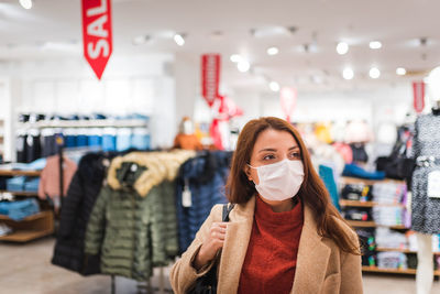 Woman wearing mask looking away at shopping mall