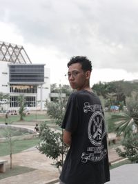 Portrait of young man standing against sky