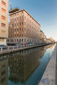 Canal by buildings against clear sky in city