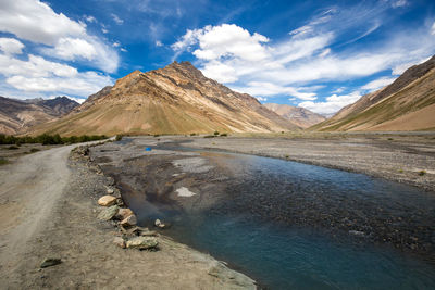 Scenic view of road by mountains against sky