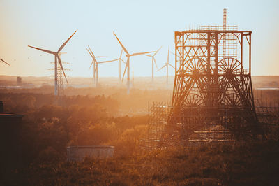 Windmills on field against sky during golden hour 