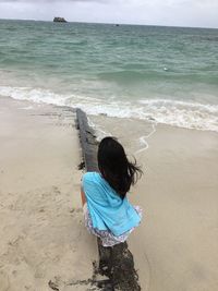 Rear view of girl sitting at beach