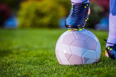 Low section of football player with soccer ball on field