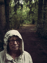 Portrait of mature woman wearing hooded shirt at forest