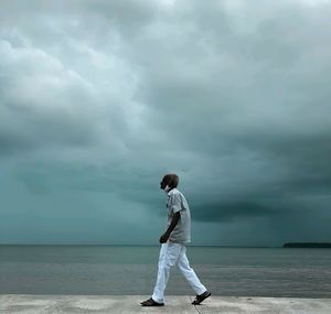 Full length of man standing on sea shore against sky