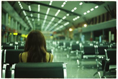 Rear view of woman sitting on seat at airport