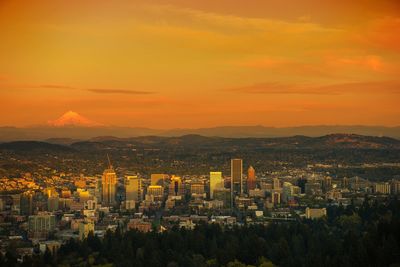 Aerial view of cityscape against orange sky during sunset