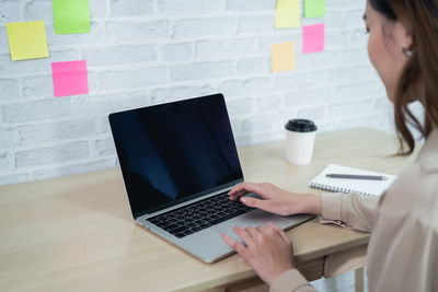 Midsection of woman using laptop on table