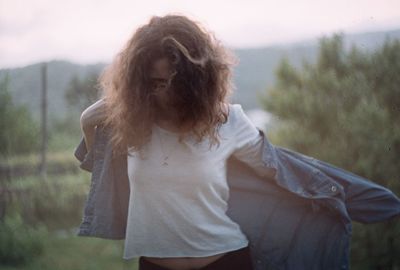 Close-up of young woman standing against trees