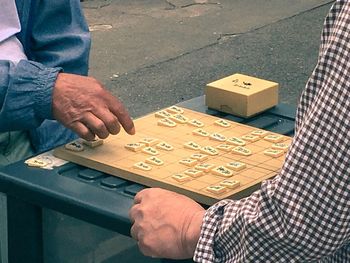 Midsection of male friends playing shogi while sitting outdoors