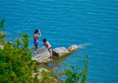 High angle view of friends on rock by sea