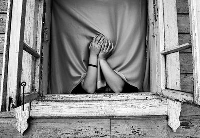 Low section of woman sitting on wooden door